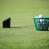 Basket of golf balls on a green field