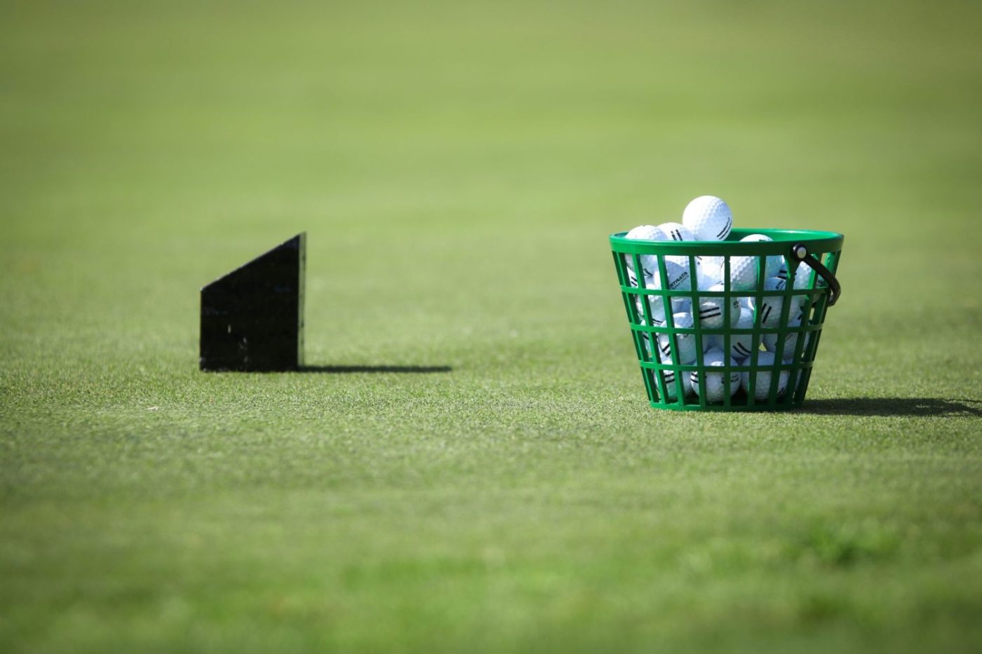 Basket of golf balls on a green field