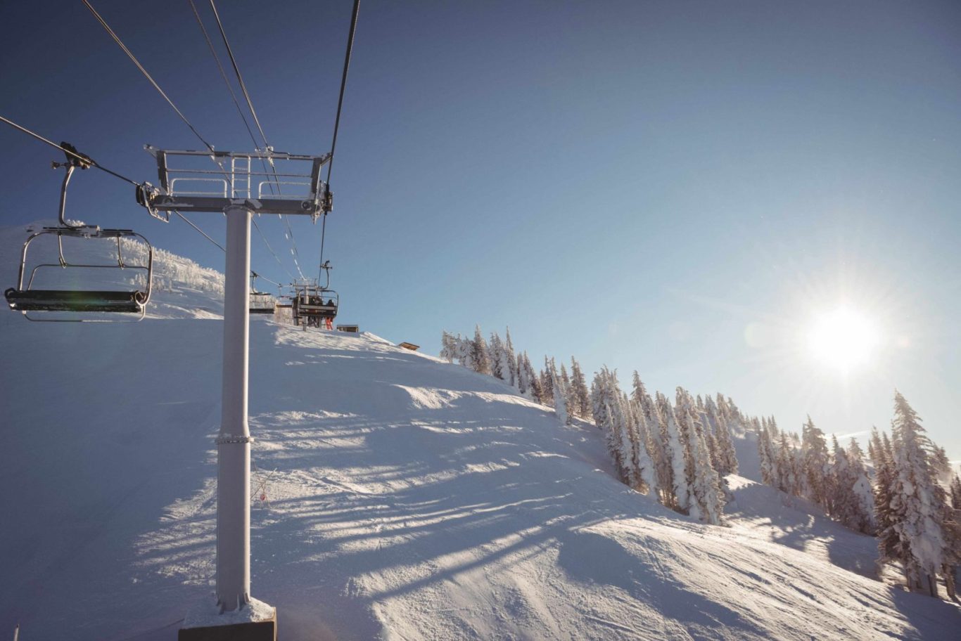 Empty ski lift in a snowy ski resort under clear skies
