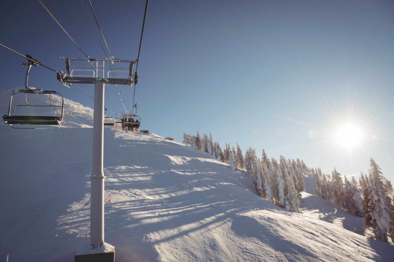 Empty ski lift in a snowy ski resort under clear skies